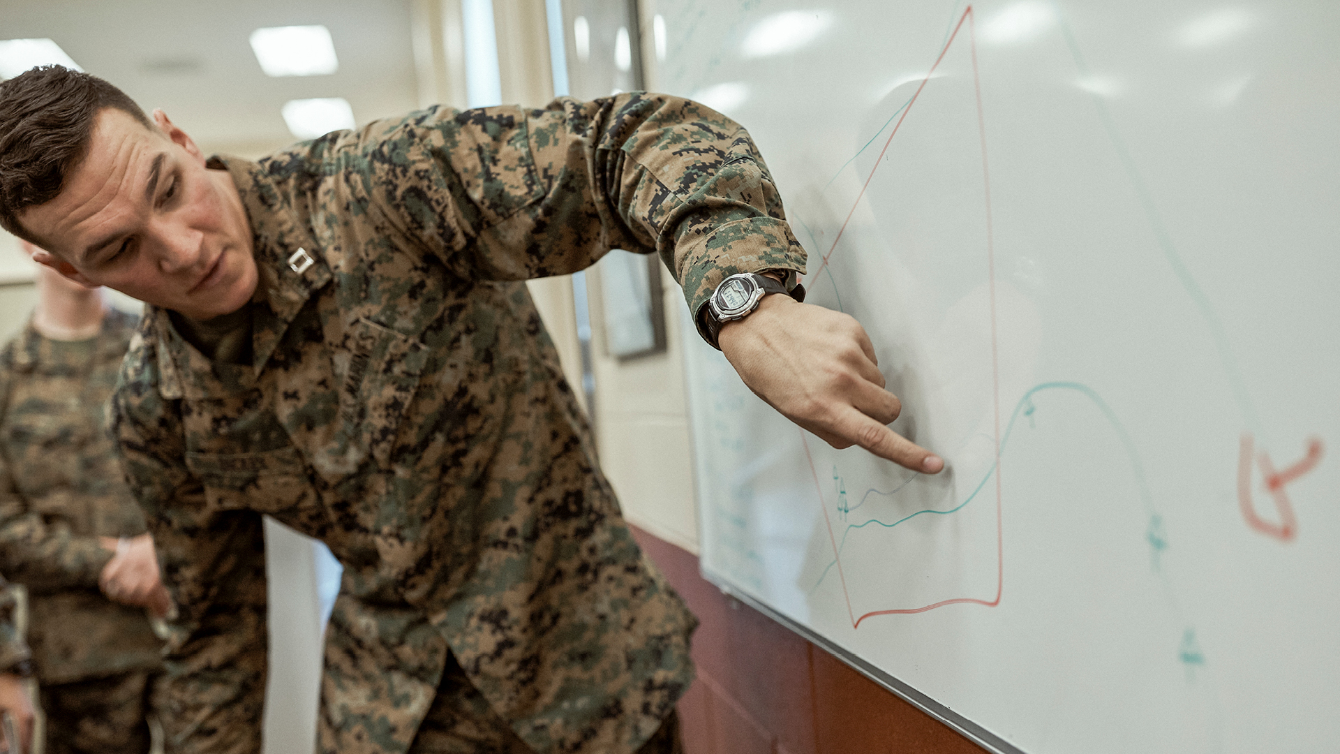 Austin Dickey pointing to a whiteboard below him