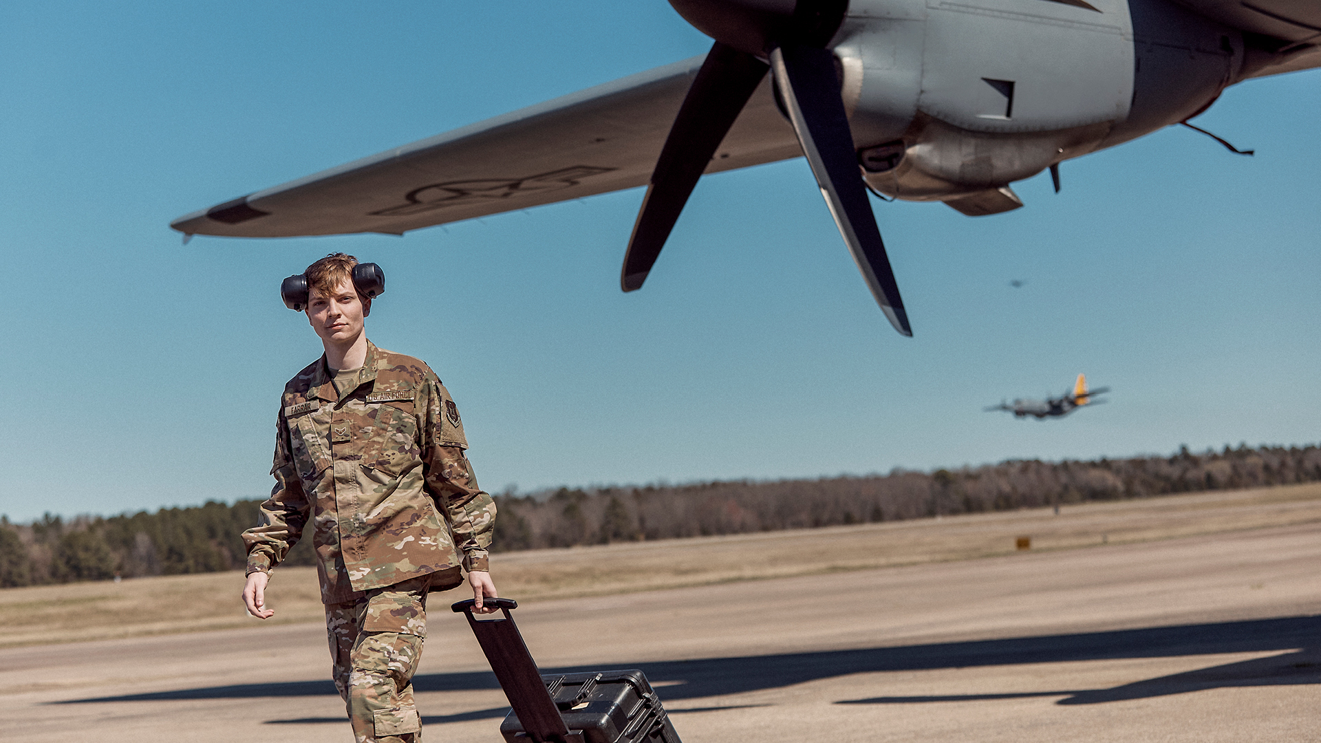 Corbin Farrar in front of the wing of an Air Force plane