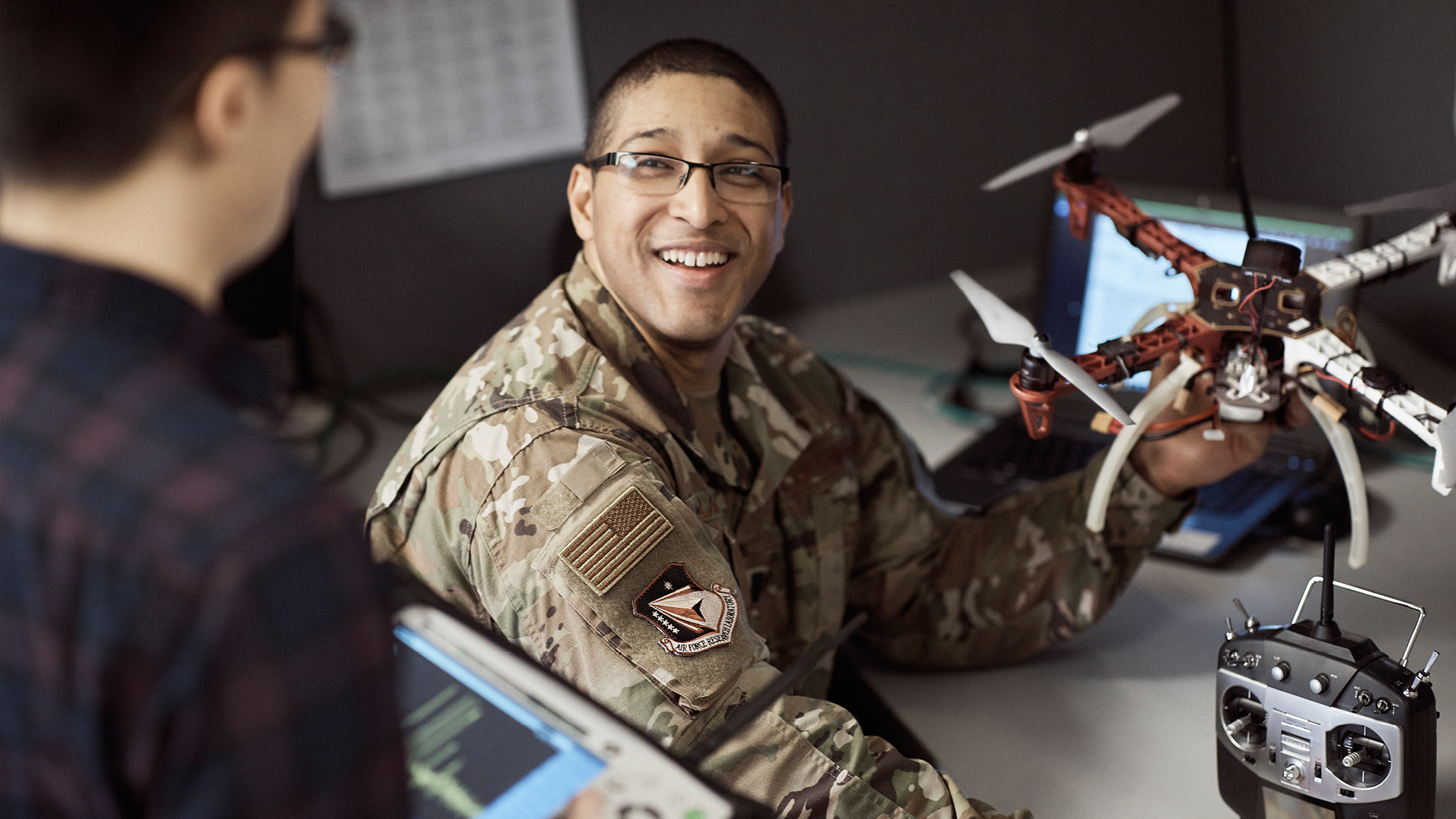 Phillip Lane smiling while showing a coworker a drone at his desk
