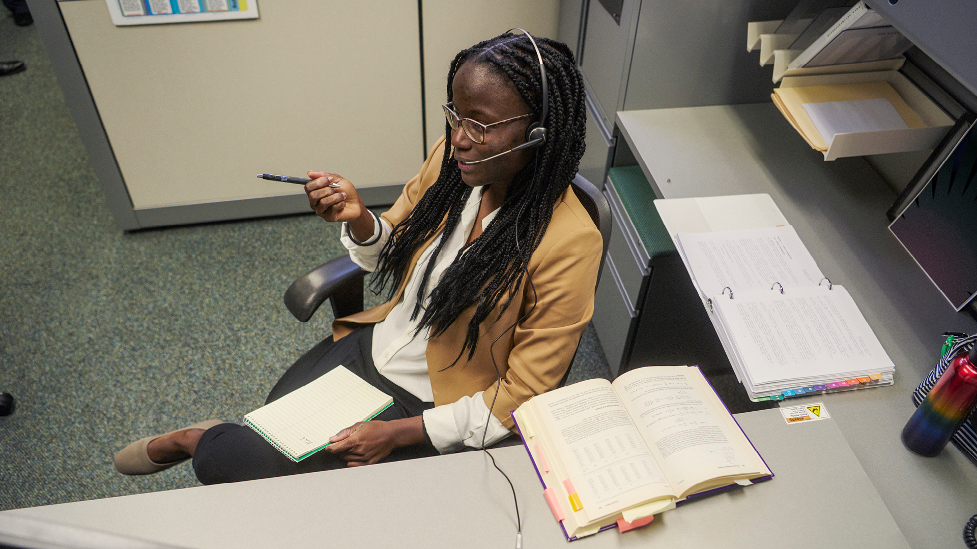Tyra Newton sitting at a desk on the phone with a pen and note pad