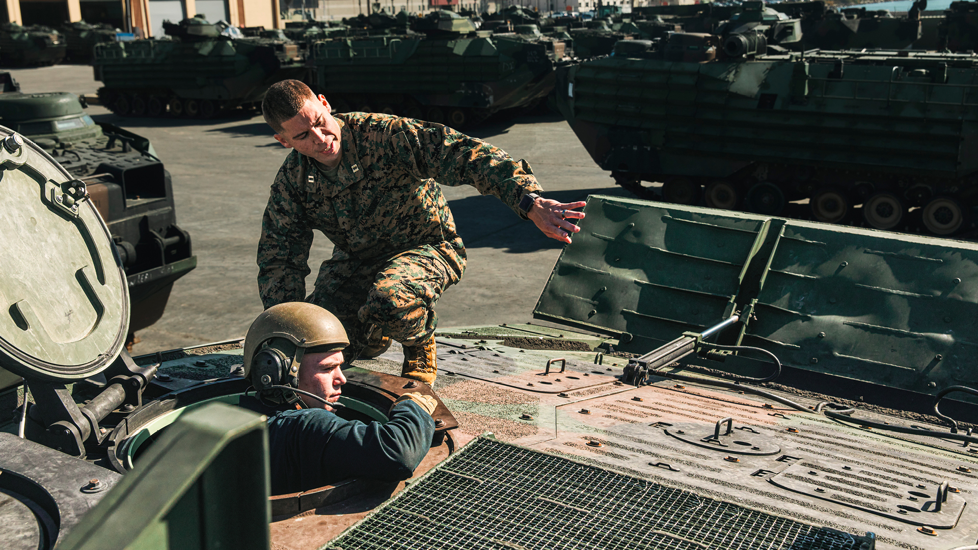 David sitting on top of a tank instructing another service memeber