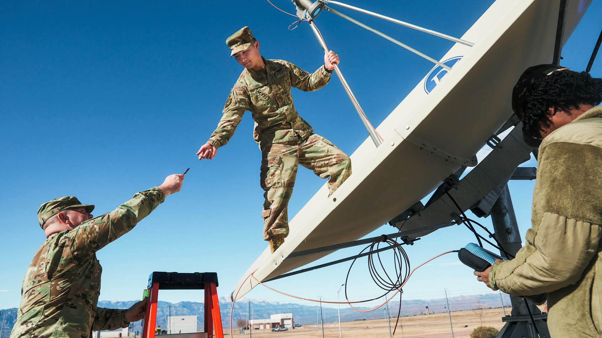 Trenton Ching working with coworkers to repair a satellite. 