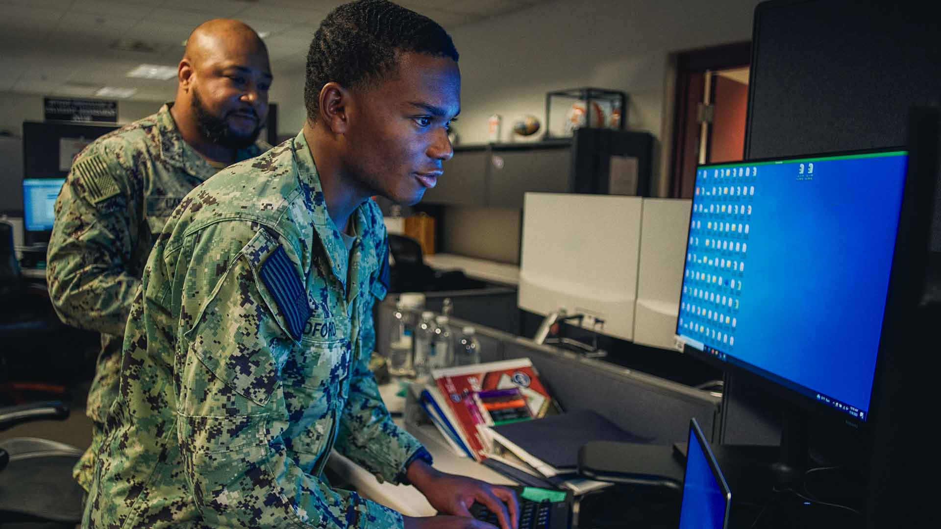Julian Bedford at a computer with a fellow service member working