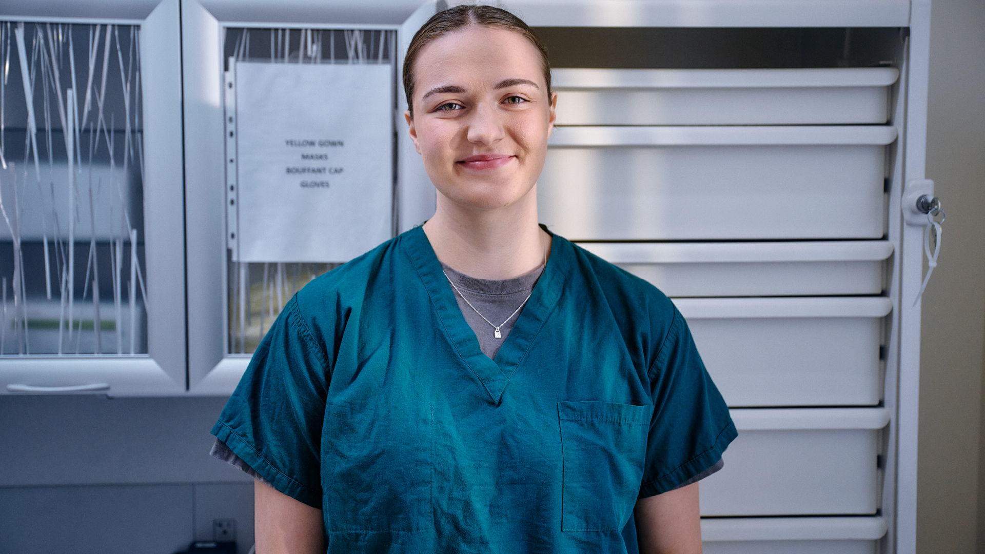 Francesca Lograsso in medical scrubs, standing in front of supply cabinets