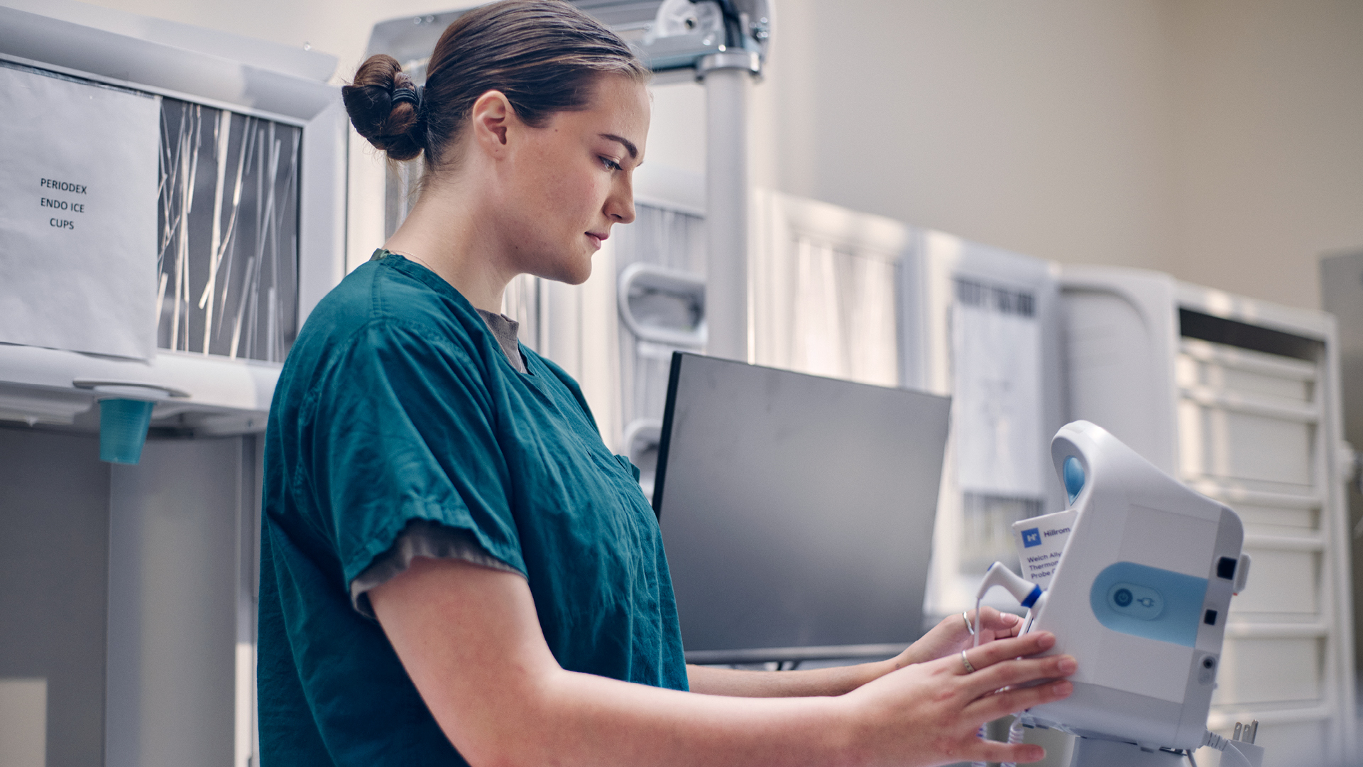 Francesca Lograsso in medical scrubs, working with a blood pressure monitor
