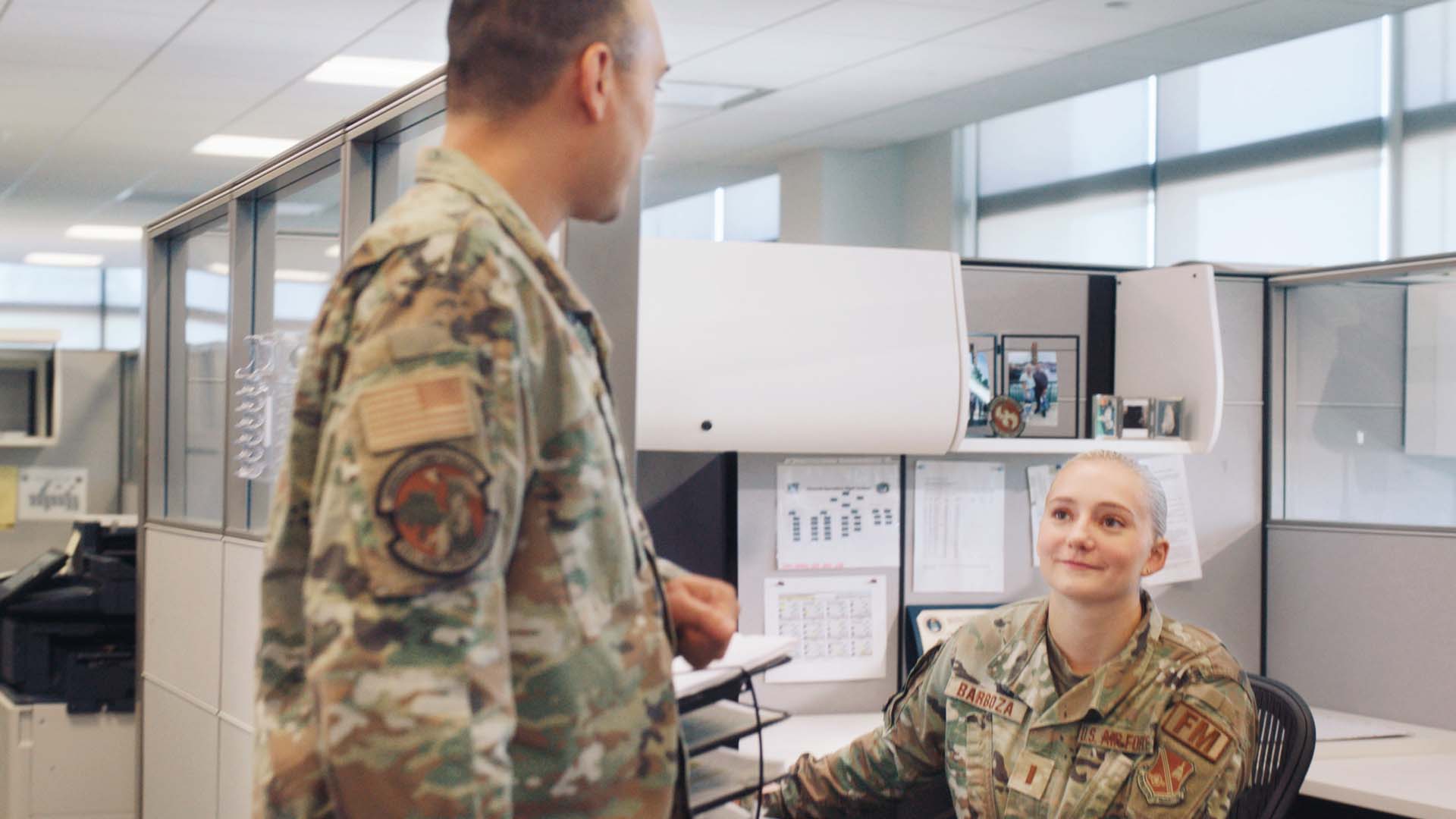 Hope Barboza sitting at her office desk, talking with another service member
