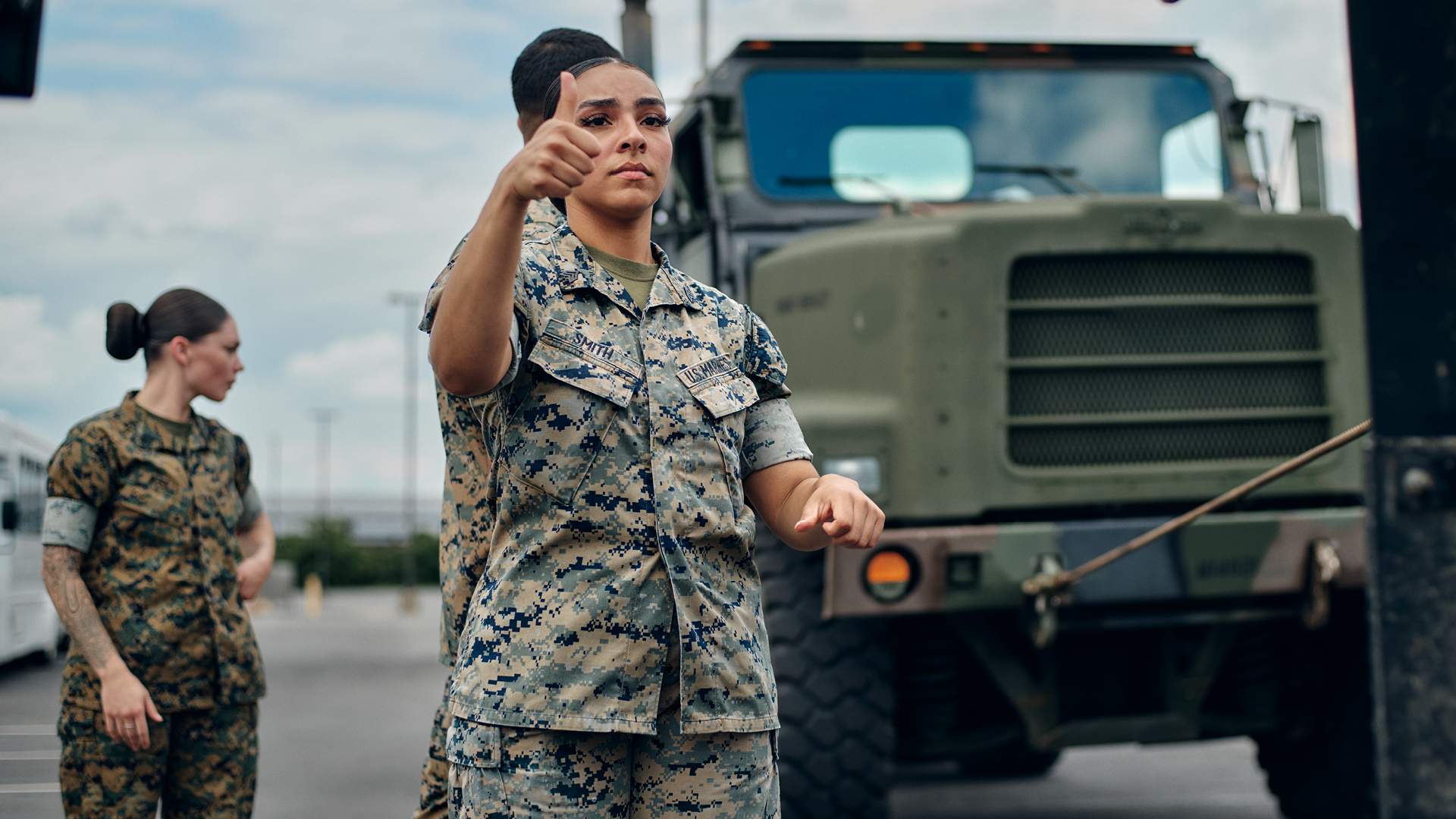 Kendyl Smith giving a thumbs up in front of a tactical truck.