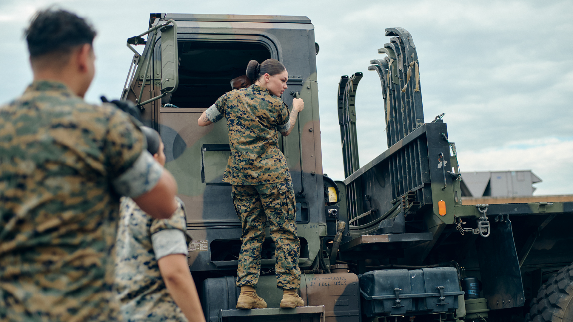 Mackenzie Musilli climbing up to the cabin of a tactical truck.