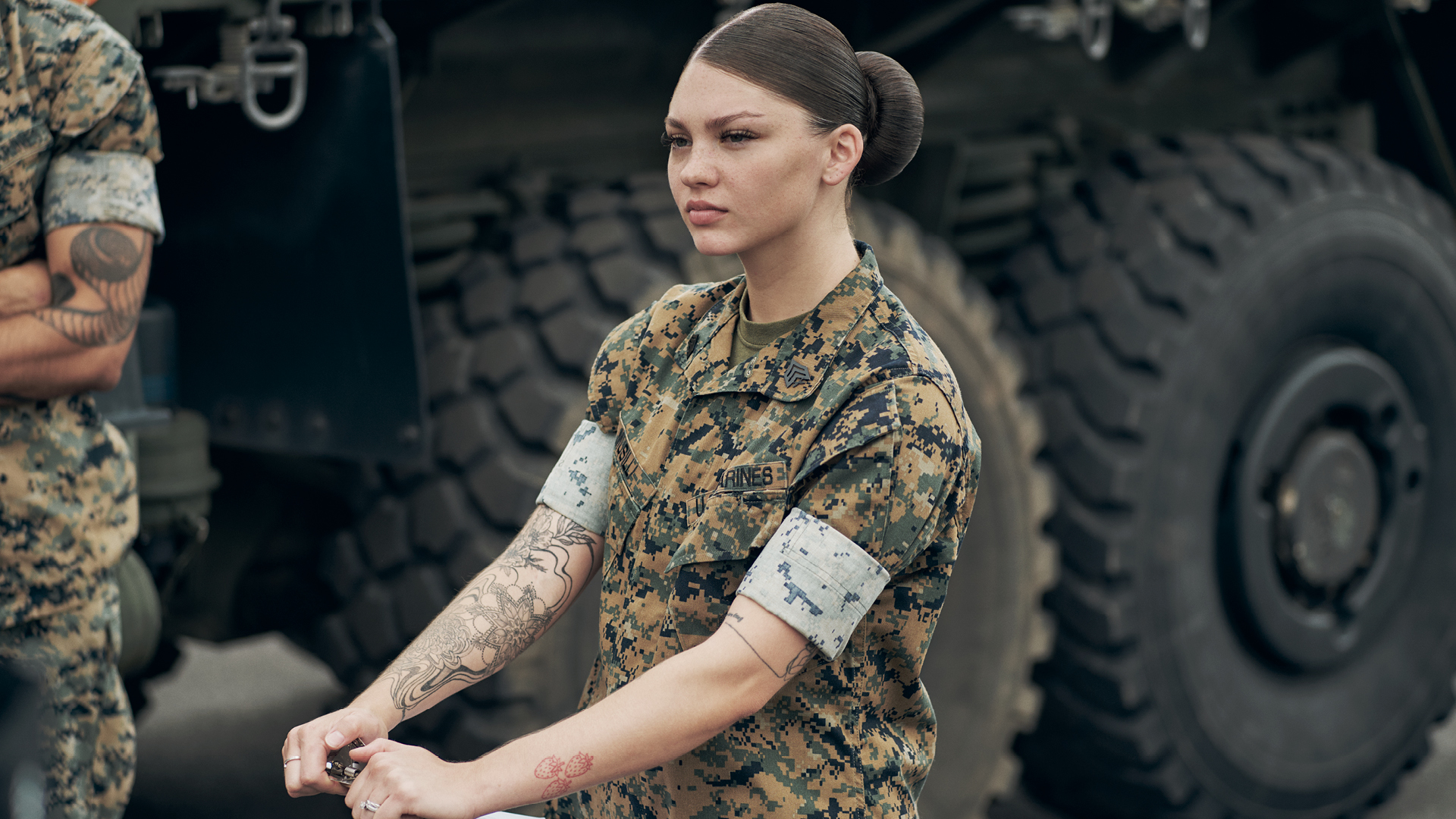 Mackenzie Musilli holding a clipboard in front of a tactical truck.